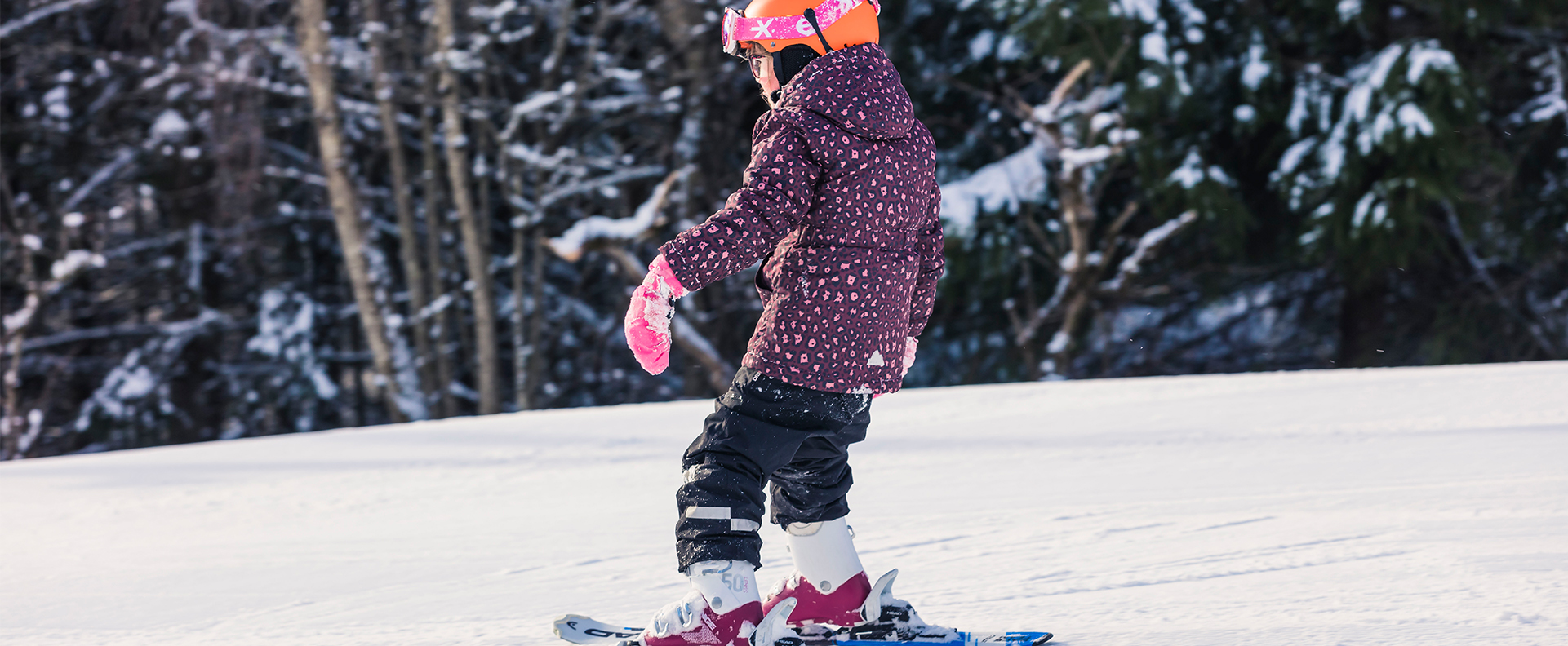 En flicka i lila overall som åker slalomskidor.
