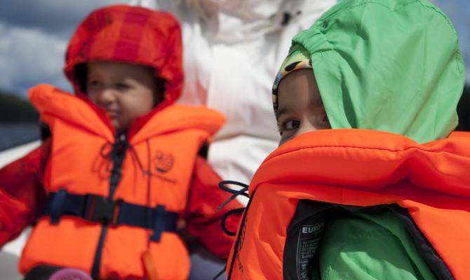 Barn som åker båt med flytväst.
