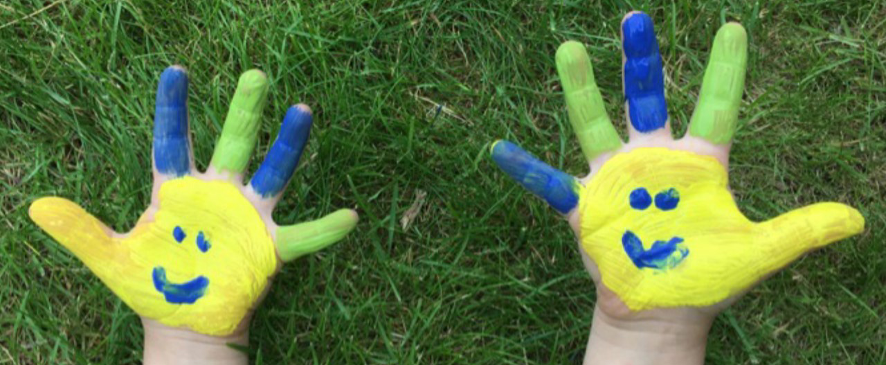 Två händer färgade i gult och blått