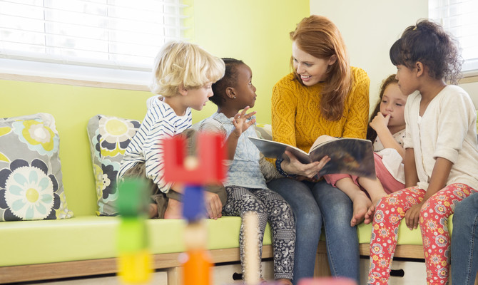 Fyra barn diskuterar innehållet i en bok tillsammans med en vuxen