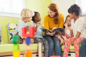 Fyra barn sitter och samtalar om innehållet i en bok tillsammans med en vuxen