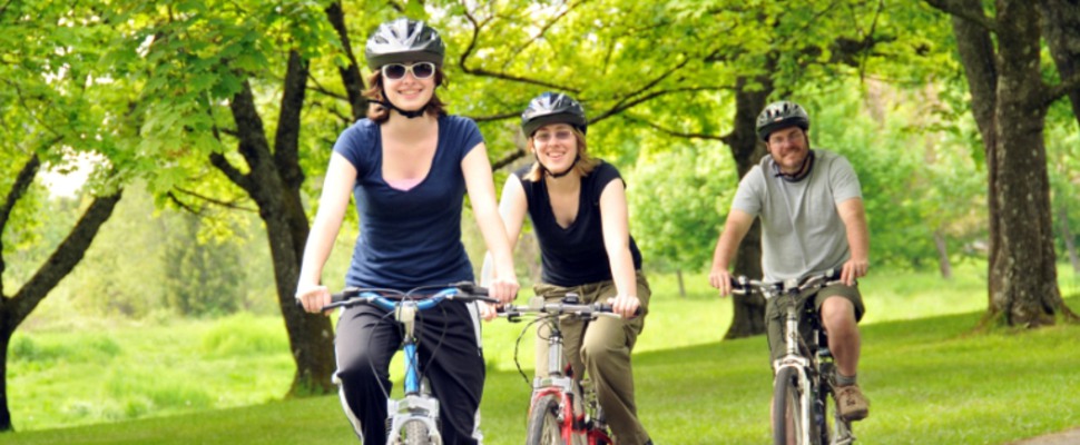 Tre personer cyklar i en park